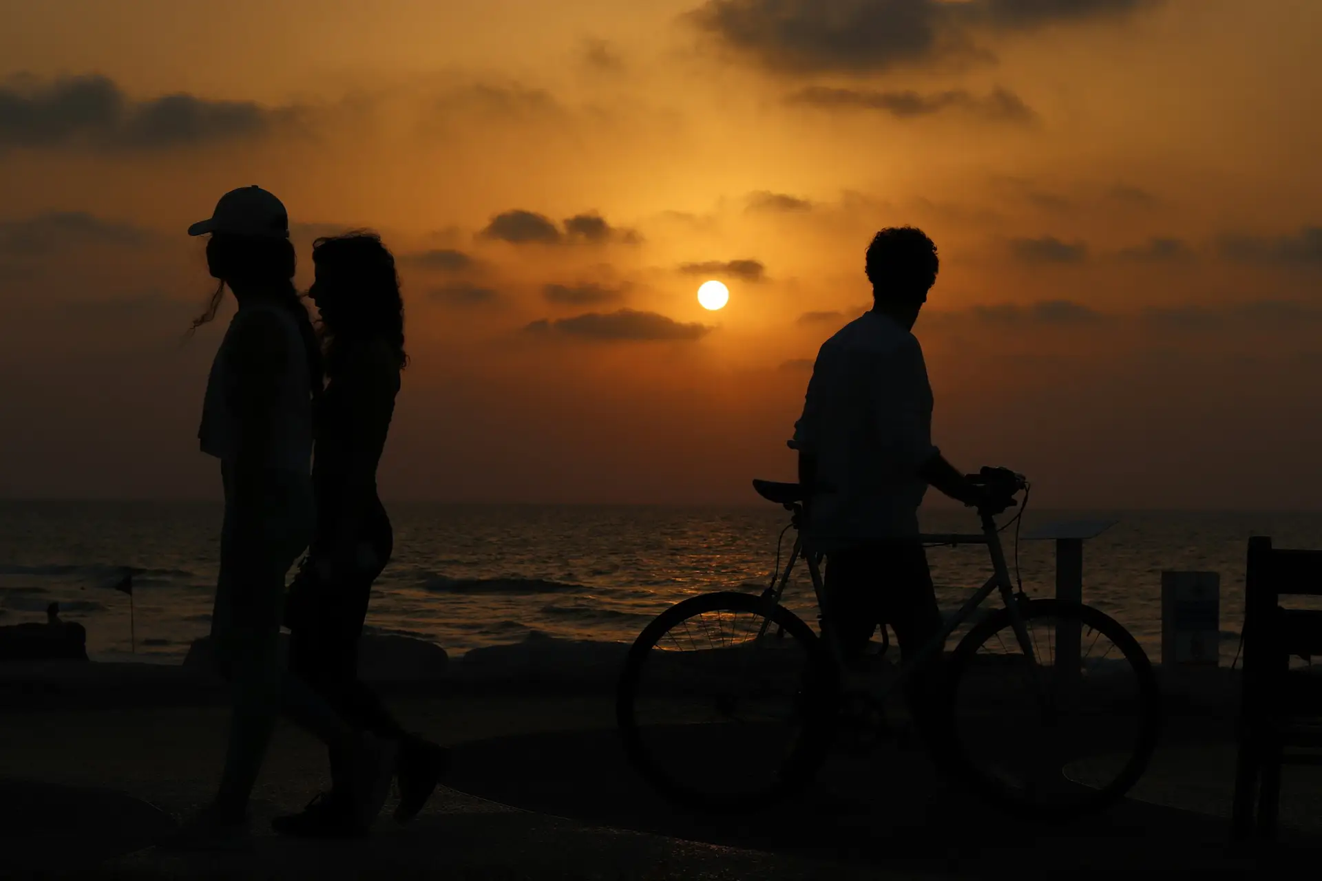 רוכב אופניים מול שקיעה בחוף תל אביב
