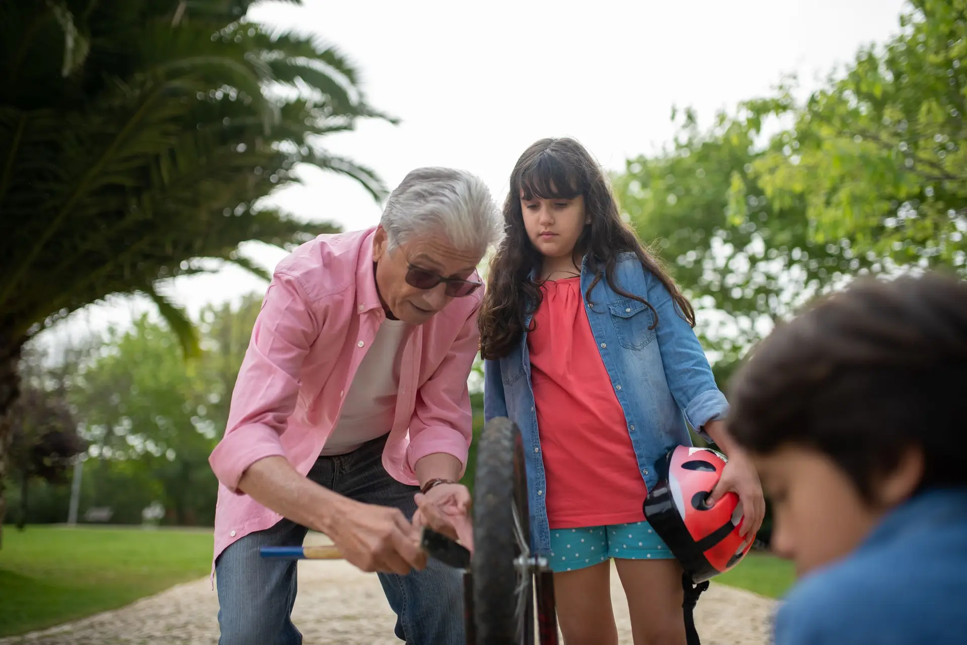 סבא וילדים מתקנים אופניים יחד בפארק
